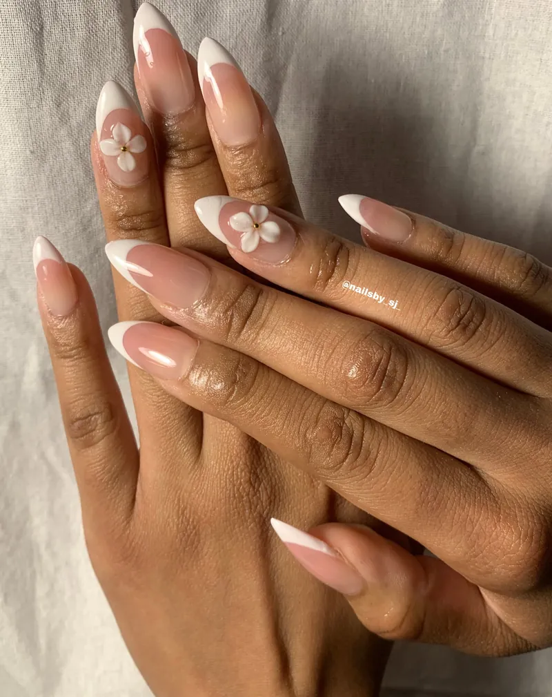 Blush almond nails with fine white French tips and small dimensional white flowers
